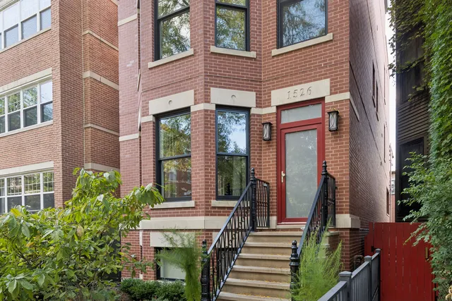 a view of a brick house with large windows and a table and chairs