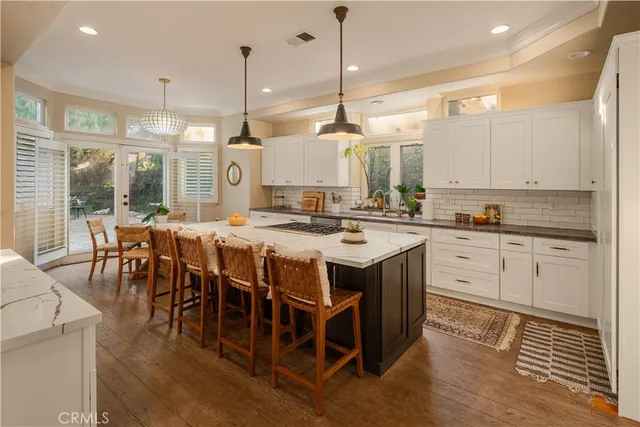 a kitchen with stainless steel appliances granite countertop a stove a sink a oven a dining table with chairs and white cabinets