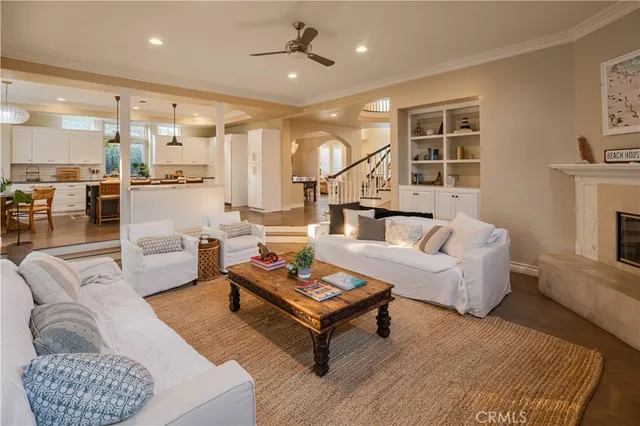 a living room with furniture a rug kitchen view and a chandelier