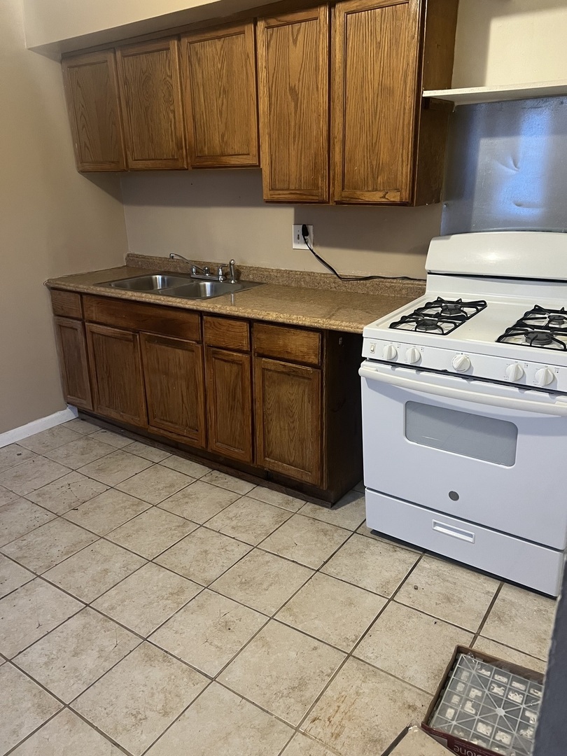 1845 East 93rd Street, Unit 2E Chicago, IL 60617 - Photo 7 of 8 a kitchen with a sink a stove cabinets and utility room