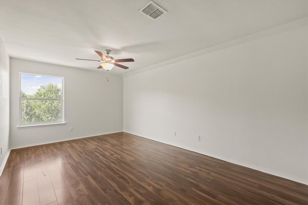 1973 Garrison Way Garland, TX 75040 - Photo 22 of 29 an empty room with wooden floor chandelier fan and windows