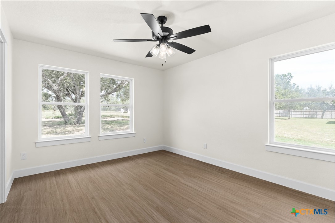 3025 Millhouse Road Copperas Cove, TX 76522 - Photo 29 of 43 an empty room with wooden floor fan and windows