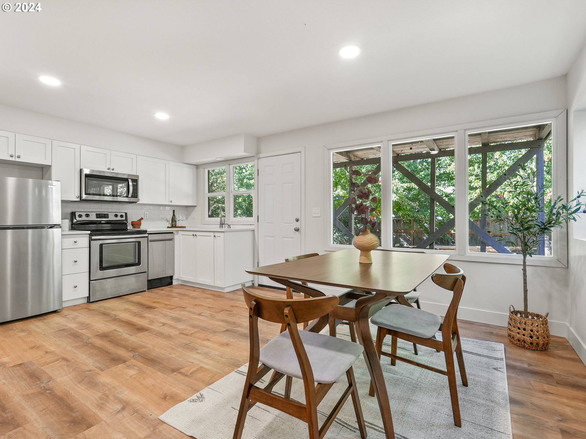 5525 Southwest Florida Street Portland, OR 97219 - Photo 27 of 44 a kitchen with stainless steel appliances granite countertop a stove top oven a sink dishwasher a dining table and chairs with wooden floor