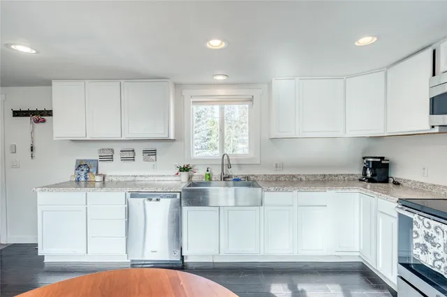 a kitchen with granite countertop white cabinets and white appliances