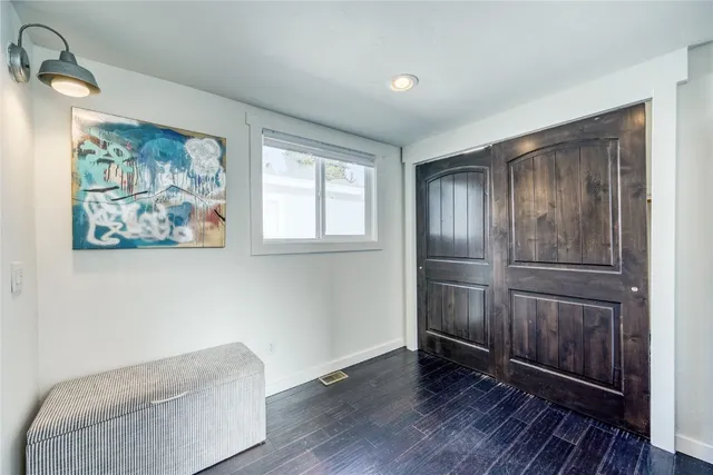 an empty room with wooden floor closet and windows