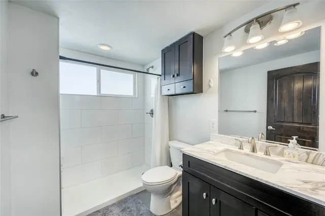 a bathroom with a granite countertop sink toilet and shower