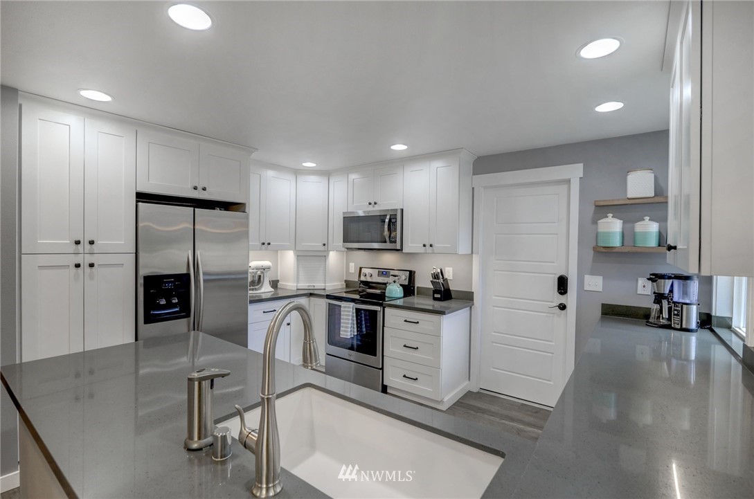 22725 2nd Place West Bothell, WA 98021 - Photo 8 of 29 an open kitchen with stainless steel appliances granite countertop a stove top oven a sink dishwasher and a refrigerator with wooden floor