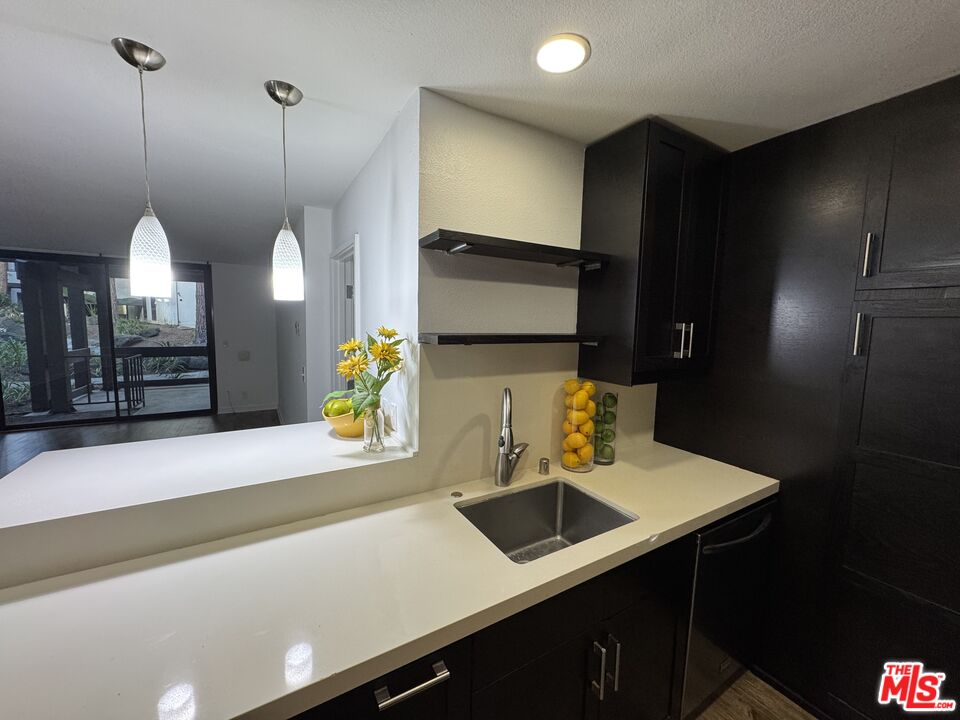 8640 Gulana Avenue, Unit K1020 Playa del Rey, CA 90293 - Photo 6 of 35 a kitchen with stainless steel appliances a sink a microwave a refrigerator a stove and white cabinets with wooden floor