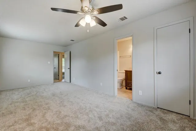 an empty room with chandelier fan and windows