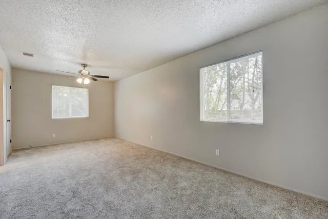 an empty room with windows and fan