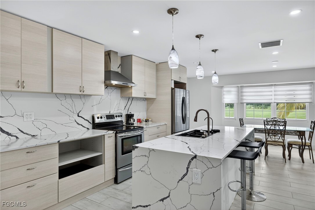 1672 Many Road North Fort Myers, FL 33903 - Photo 10 of 50 a kitchen with a stove a sink a kitchen island with a dining table and chairs