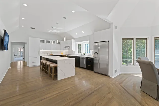 a large kitchen with stainless steel appliances granite countertop a stove top oven a sink dishwasher a dining table and chairs with wooden floor