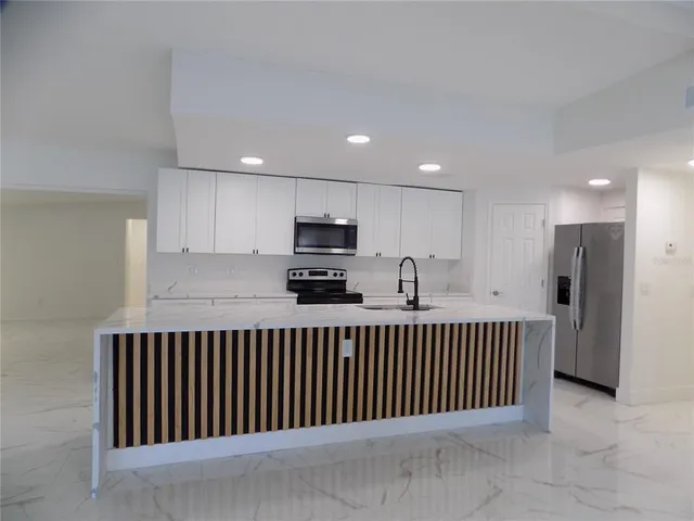 a view of kitchen with stainless steel appliances granite countertop lots of white cabinets