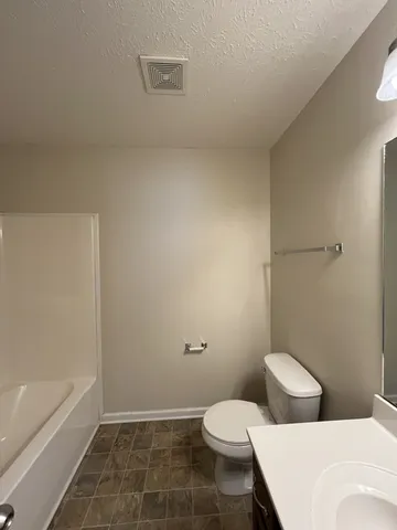 a white toilet sitting next to a bath tub