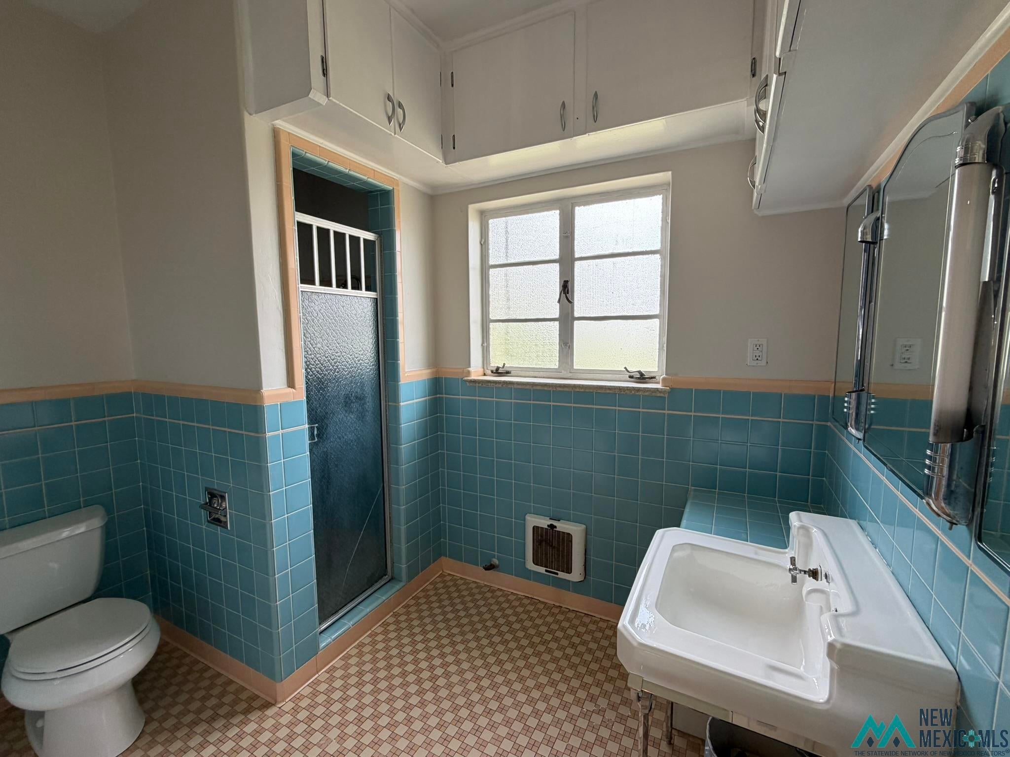 570 Curry Road North Clovis, NM 88101 - Photo 38 of 59 Bathroom featuring blue wall tiling, a pedestal sink, white cabinetry, frosted window, and a shower enclosure