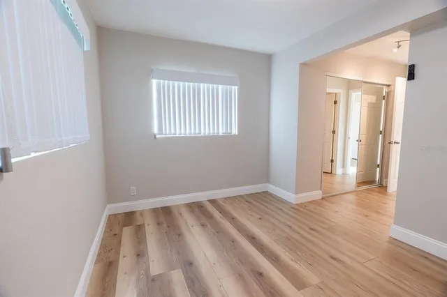 a view of an empty room with wooden floor and a window