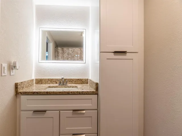a bathroom with a granite countertop sink and a mirror