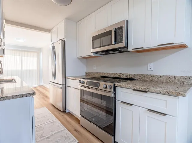 a kitchen with granite countertop a refrigerator stove and microwave