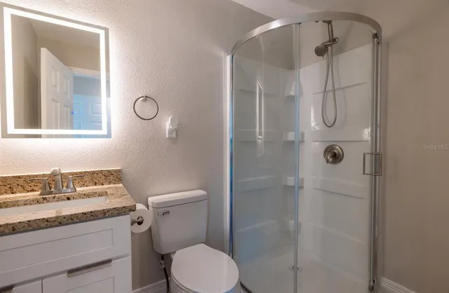 a bathroom with a granite countertop sink toilet and shower