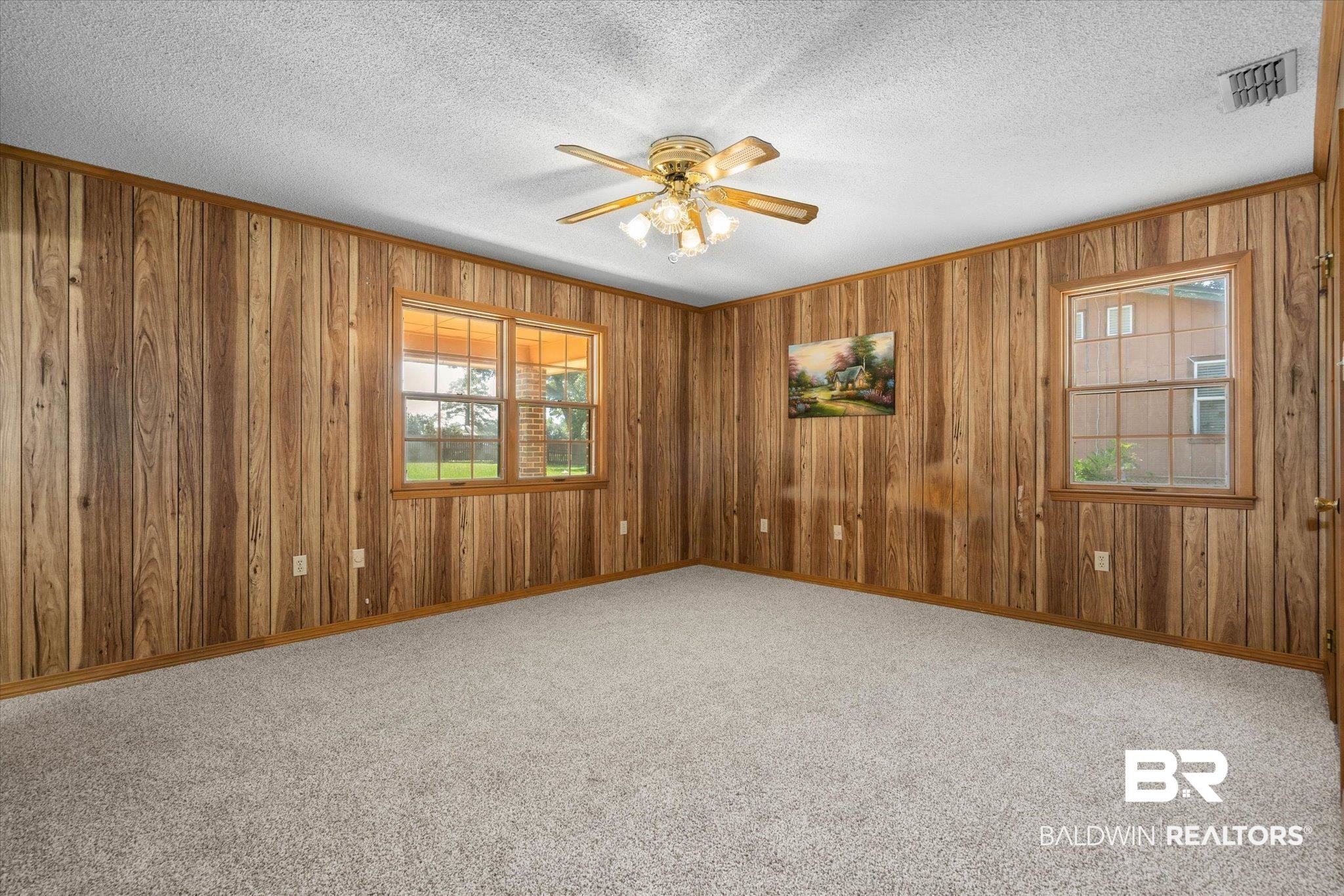 5503 Darring Street Satsuma, AL 36572 - Photo 13 of 31 Carpeted spare room with ceiling fan, wooden walls, a textured ceiling, and ornamental molding