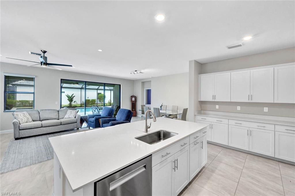 18298 Ridgeline Drive Estero, FL 33928 - Photo 13 of 49 Kitchen featuring white cabinetry, stainless steel dishwasher, an island with sink, ceiling fan, and recessed lighting