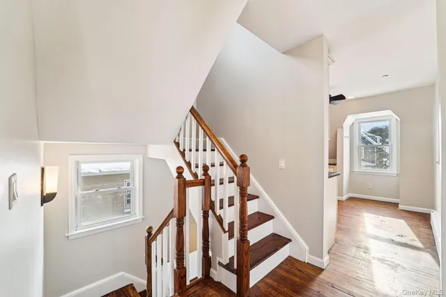 an empty room with wooden floor chandelier fan and windows