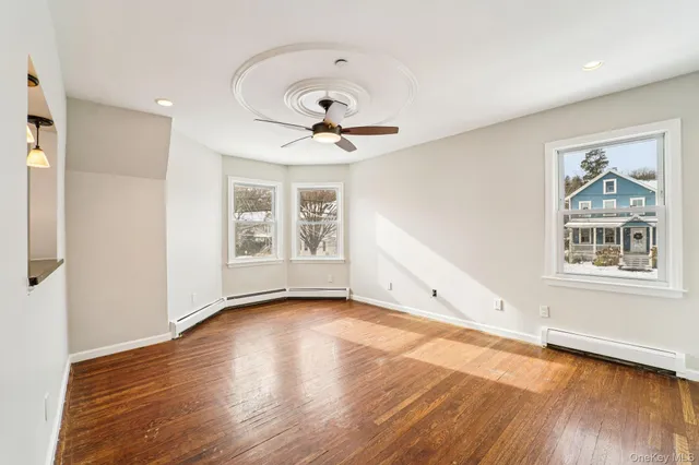 a view of empty room with wooden floor and fan