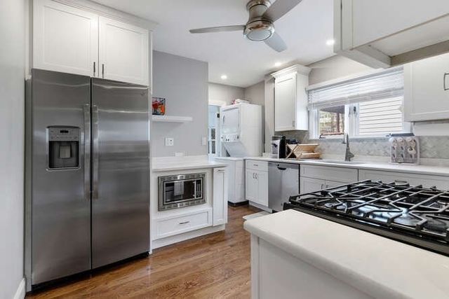 a kitchen with stainless steel appliances a refrigerator a sink and white cabinets