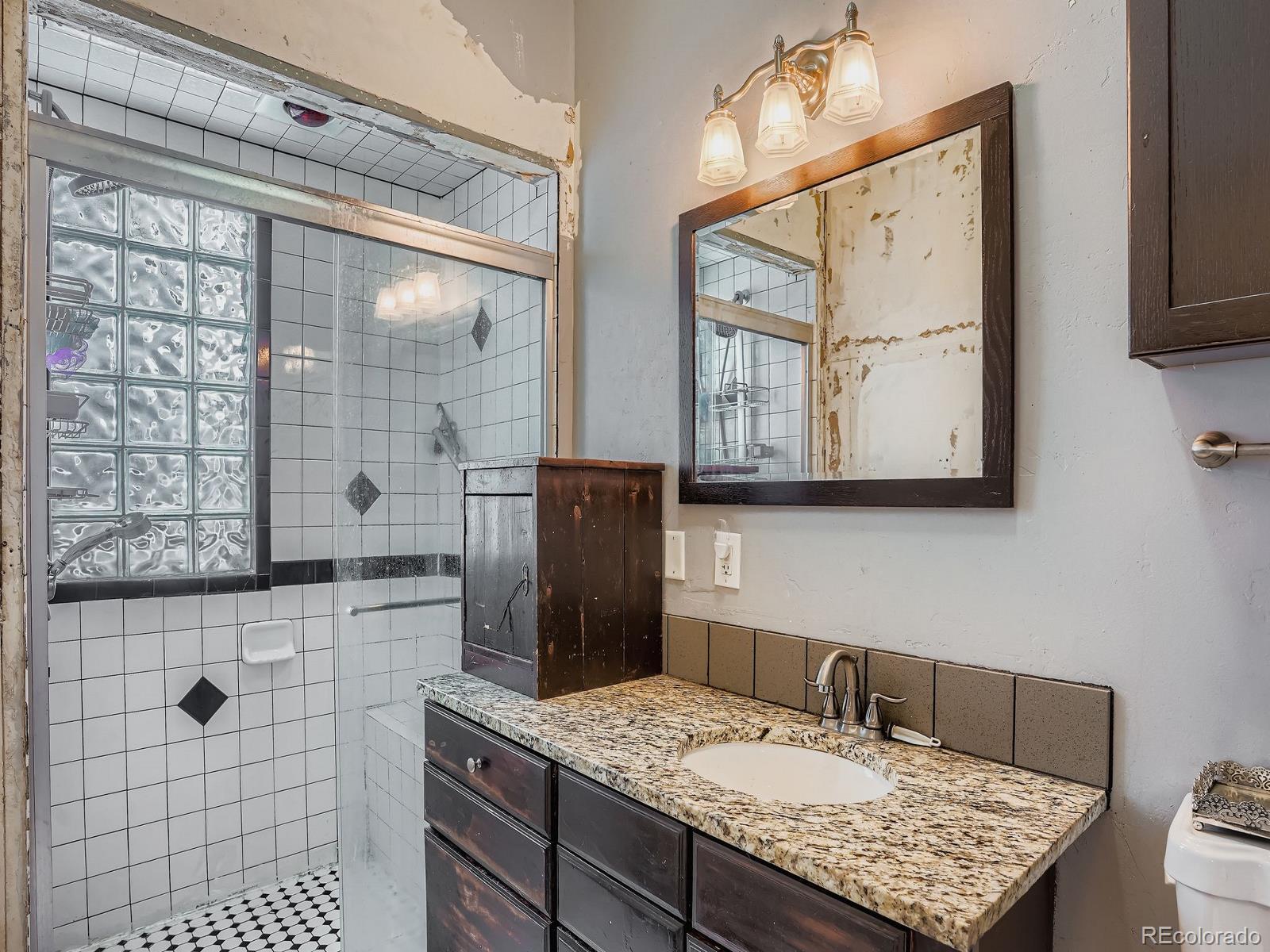 2516 North Marion Street Denver, CO 80205 - Photo 30 of 31 a bathroom with a granite countertop sink a mirror and shower