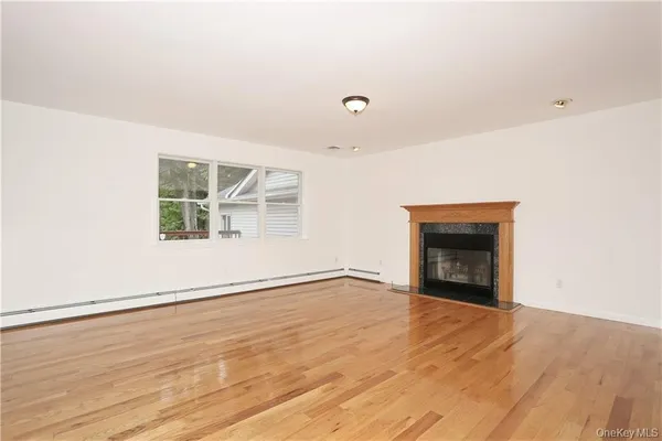 an empty room with wooden floor fireplace and windows