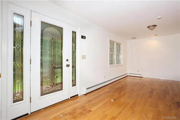 a view of an empty room with window and wooden floor