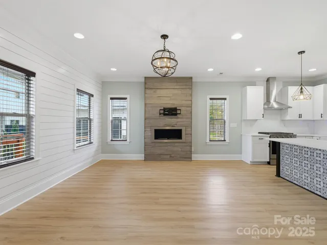 a view of an empty room with a kitchen and a window