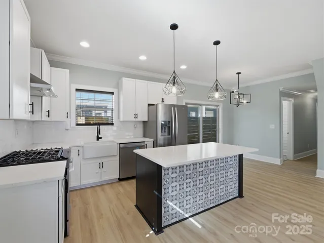 a kitchen with stainless steel appliances kitchen island granite countertop a stove a sink dishwasher and a wooden cabinets