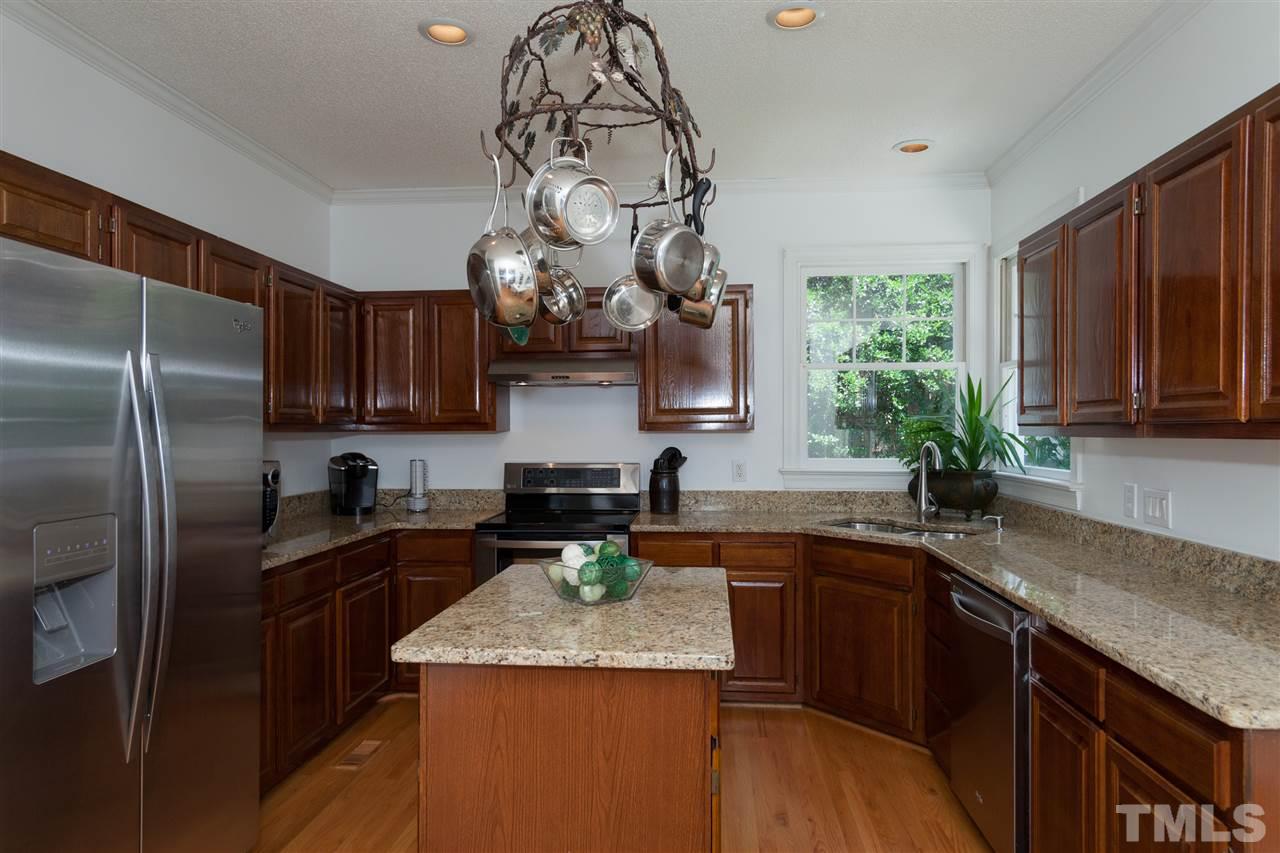 5817 Raddington Street Raleigh, NC 27613 - Photo 10 of 25 a kitchen with stainless steel appliances granite countertop a sink a stove and a wooden cabinets