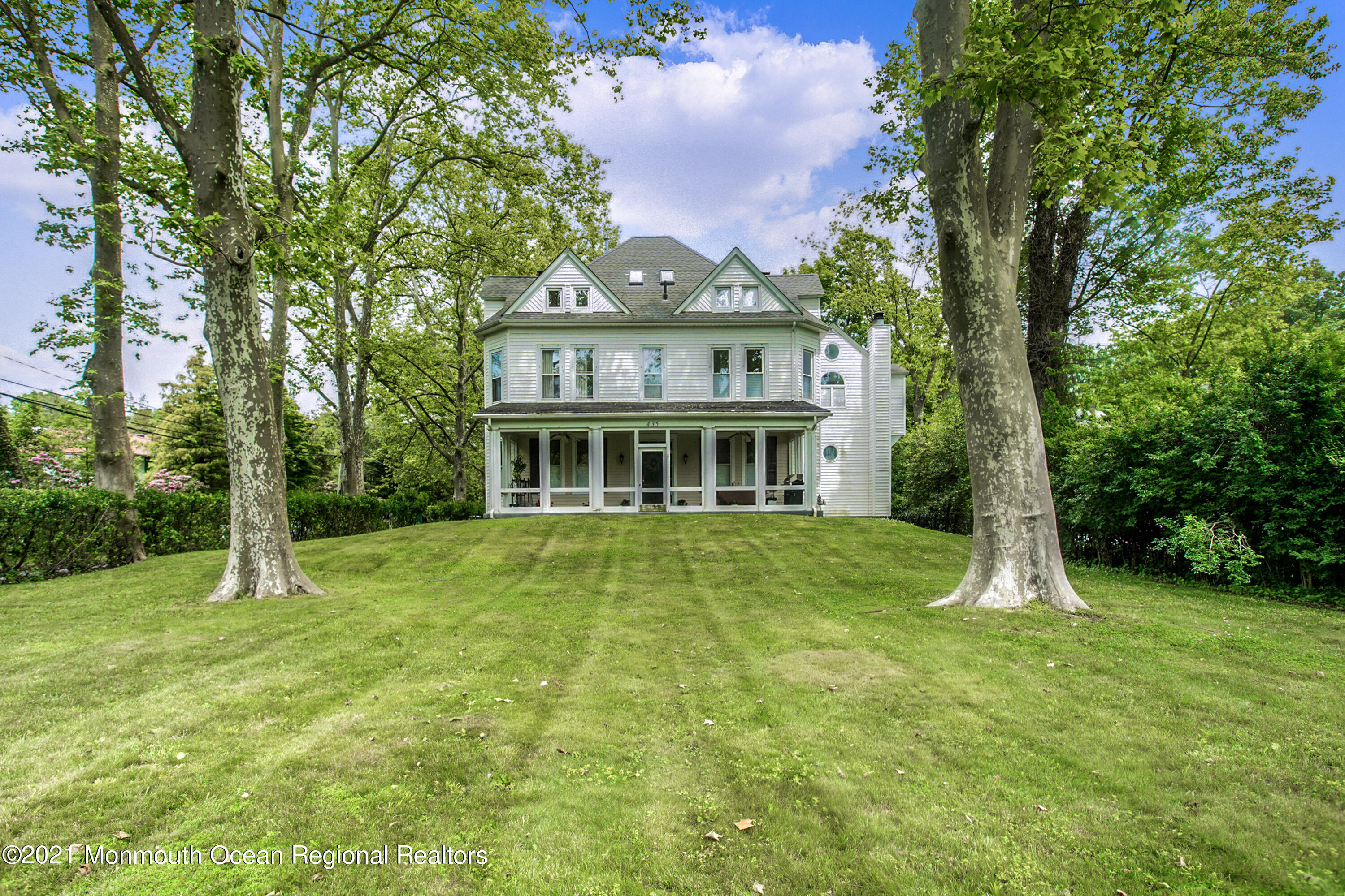 a view of a big house with a big yard and large trees