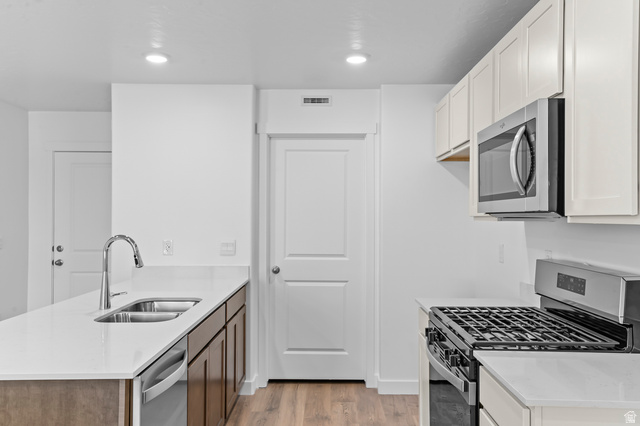 1851 East Corriente Drive, Unit 1166 Salem, UT 84653 - Photo 5 of 16 Kitchen with stainless steel appliances, light stone countertops, a peninsula, light wood-style flooring, and recessed lighting