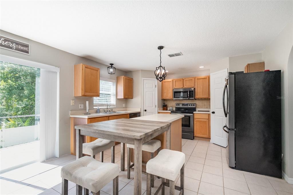 149 Circle Hill Road Sanford, FL 32746 - Photo 2 of 30 a kitchen with a refrigerator a stove a dining table and chairs with wooden floor