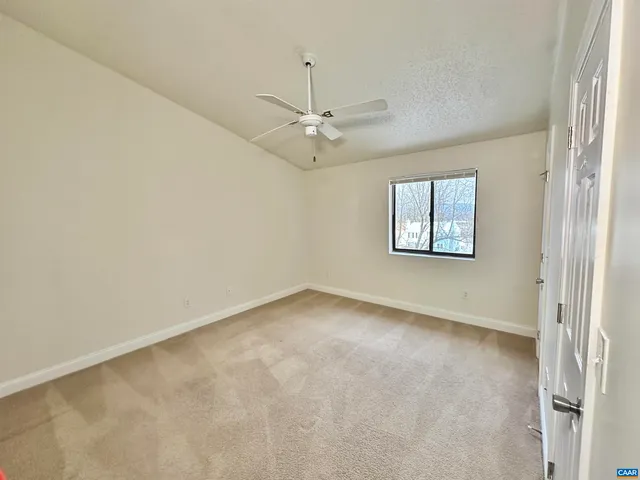 an empty room with windows and fan