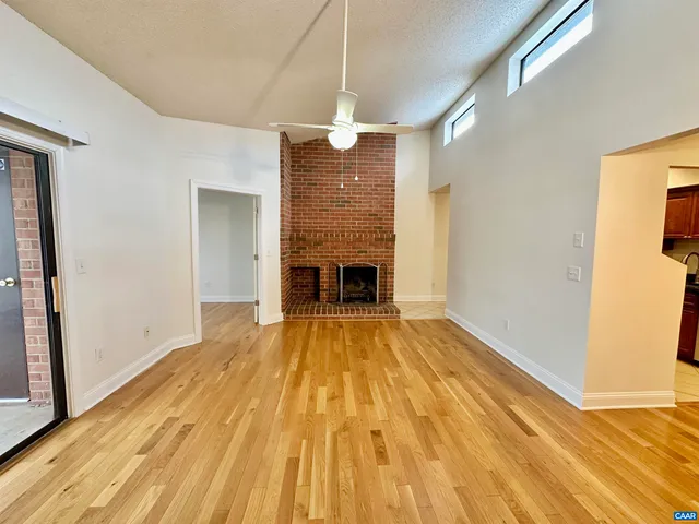 a view of empty room with wooden floor and fireplace