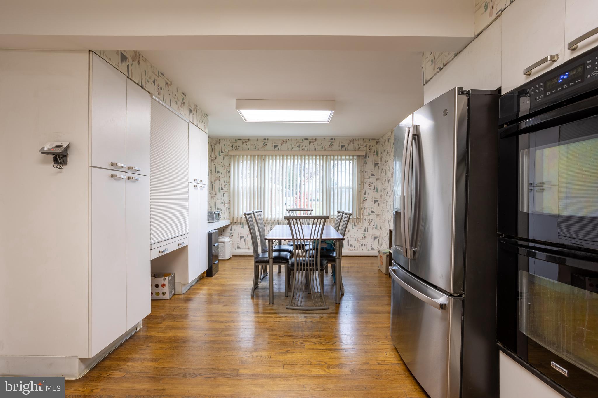 3215 Northbrook Road Baltimore, MD 21208 - Photo 13 of 48 a kitchen with stainless steel appliances granite countertop a refrigerator a stove a dining table and chairs with wooden floor
