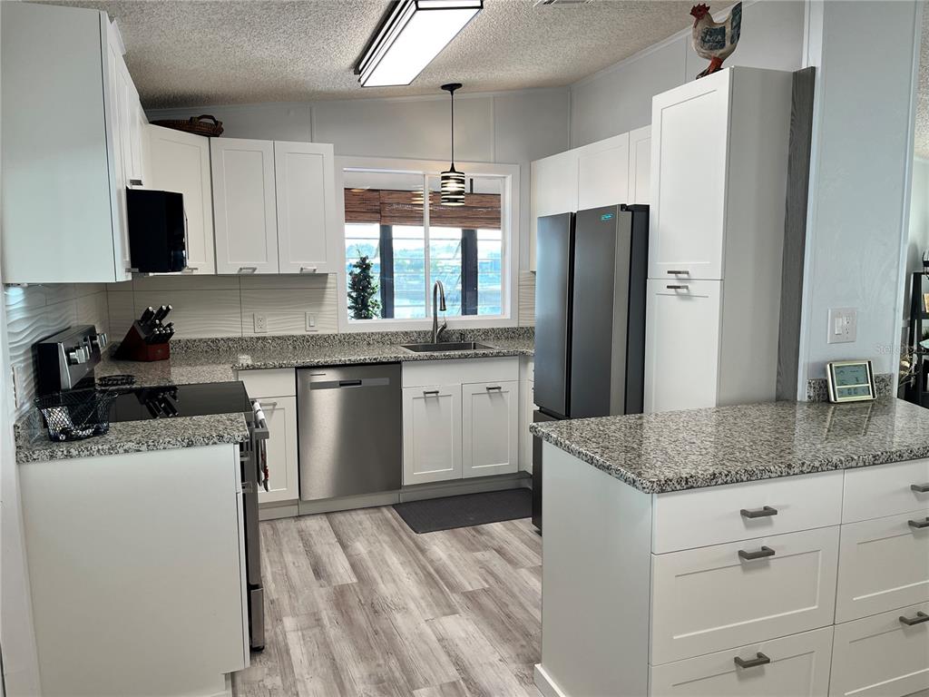 6803 Mt Pleasant Road Northeast, Unit 33 St. Petersburg, FL 33702 - Photo 8 of 28 a kitchen with granite countertop a sink stove and refrigerator