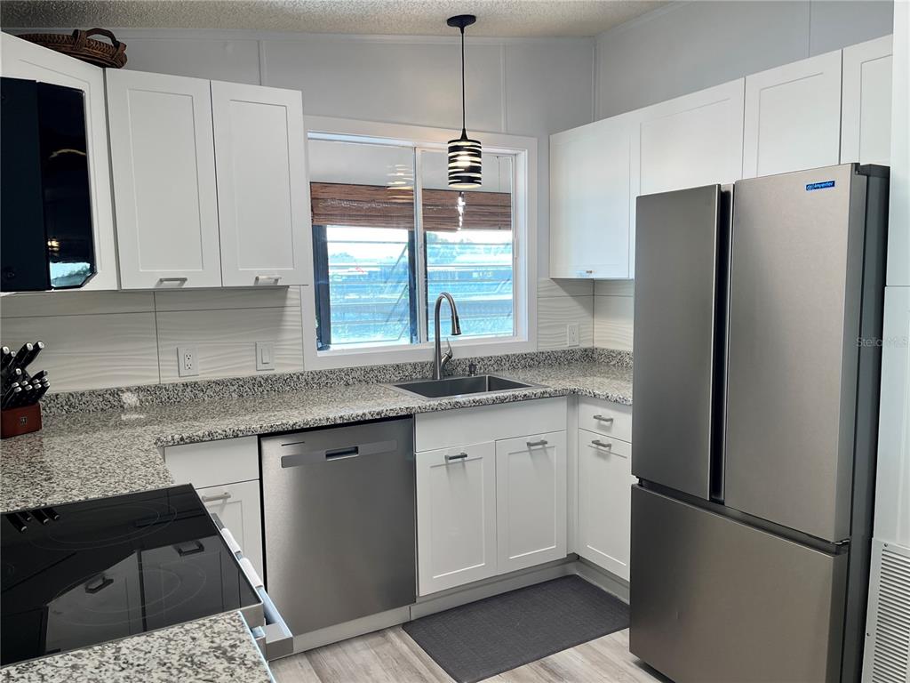 6803 Mt Pleasant Road Northeast, Unit 33 St. Petersburg, FL 33702 - Photo 9 of 28 a kitchen with stainless steel appliances granite countertop a refrigerator a sink and white cabinets