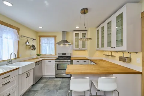 a kitchen that has a sink a stove and chairs