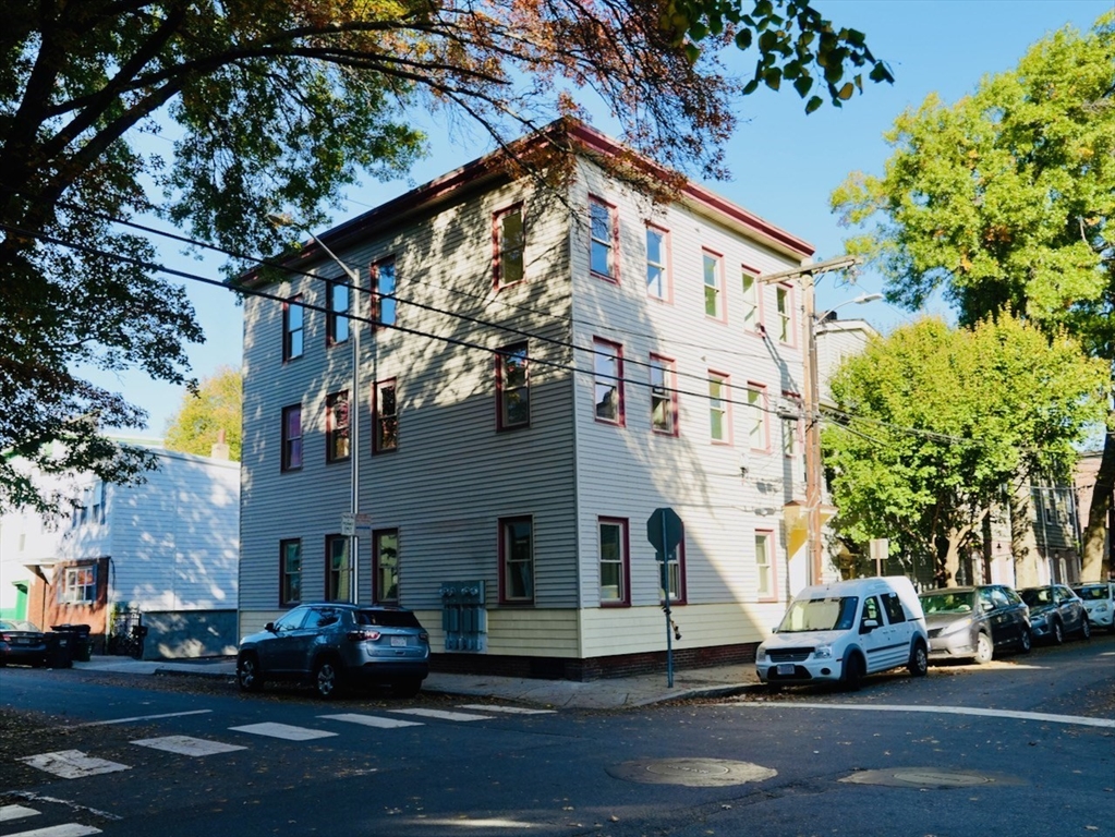 a view of a white building among the street with cars