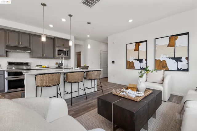 a living room with furniture kitchen view and a wooden floor