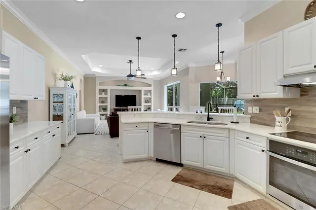 a large white kitchen with granite countertop a sink and cabinets