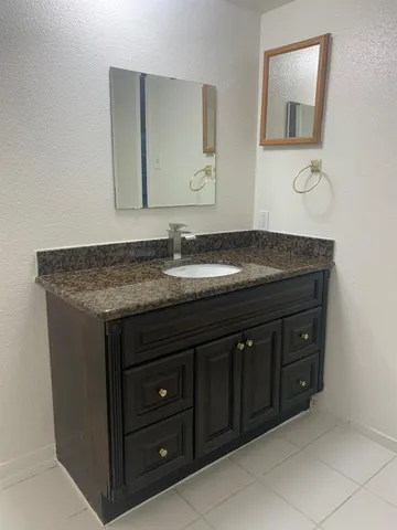 a bathroom with a granite countertop sink and a mirror
