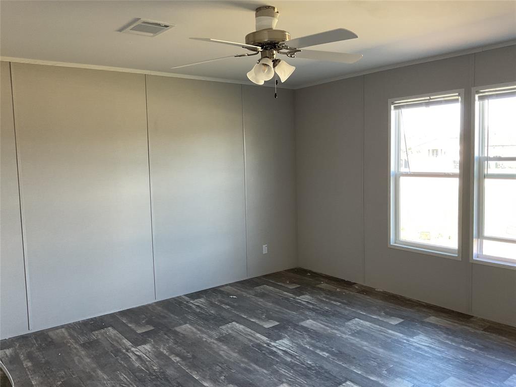 137 Firefly Drive Springtown, TX 76082 - Photo 9 of 12 Room with wood-finish flooring, two large windows, a ceiling fan with integrated lighting, and crown molding