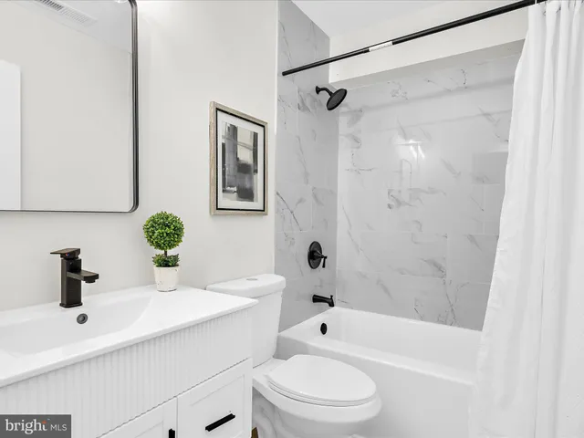 a bathroom with a sink a toilet a mirror a shower and a bathtub