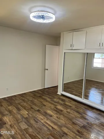 an empty room with wooden floor cabinet and windows